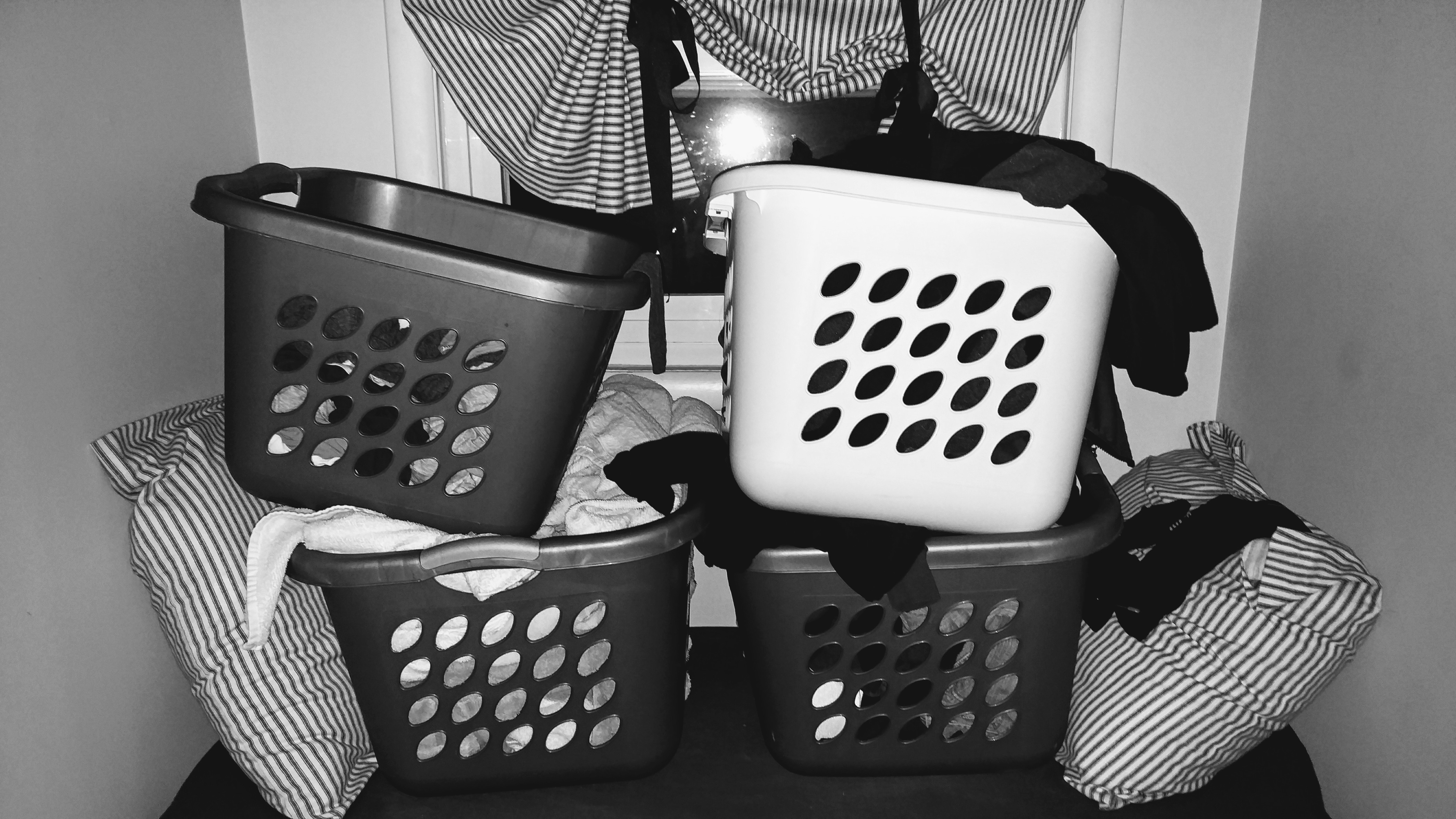 Four baskets of clean laundry stacked by a window
